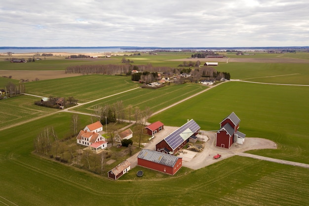 Widok Z Góry Krajobrazu Wiejskiego W Słoneczny Wiosenny Dzień. Farma Z Systemem Fotowoltaicznych Paneli Słonecznych Na Dachu Budynku, Stodoły Lub Domu.