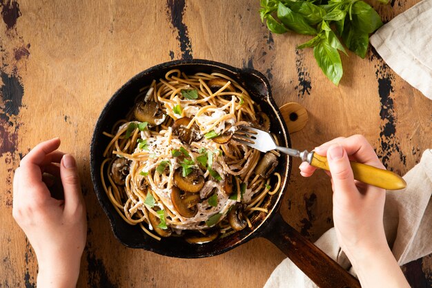 Widok z góry makaronu spaghetti z pieczarkami i sosem śmietanowym na drewnianym rustykalnym