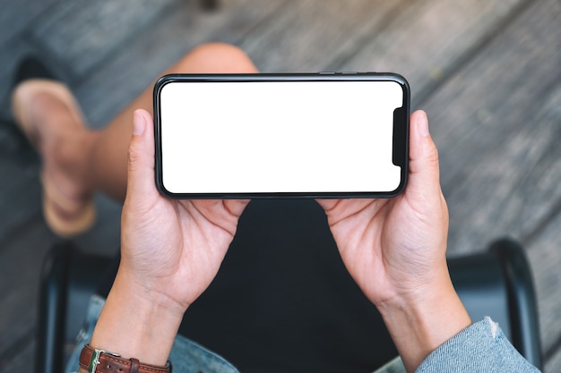 Widok z góry makieta obrazu kobiety trzymającej czarny telefon komórkowy z pustym białym ekranem pulpitu