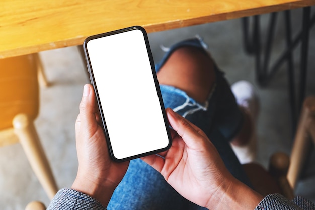 Widok z góry makieta obrazu kobiety trzymającej telefon komórkowy z pustym białym ekranem pulpitu