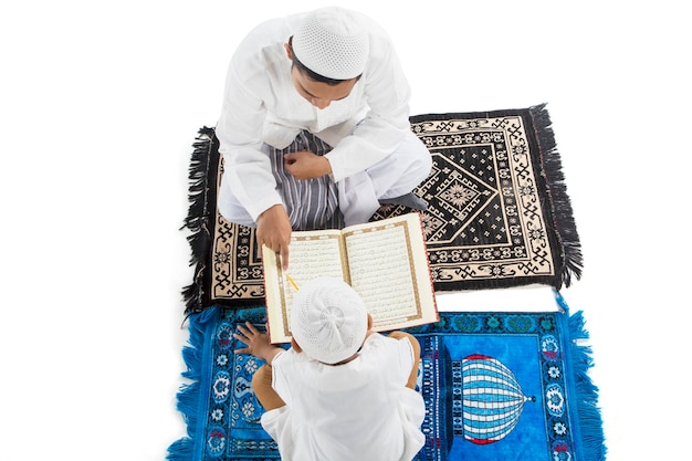 Widok z góry małego chłopca uczącego się czytać Koran z ojcem