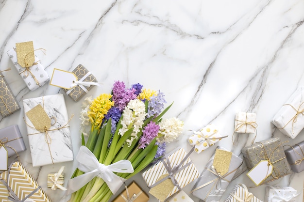 Widok z góry modna kompozycja z świątecznymi zapakowanymi pudełkami na prezenty wstążką z kokardą ozdobioną kwiatami kwitnącymi