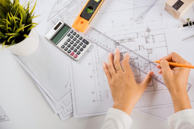 Zdjęcie widok z góry na architekta rysującego z linijką na papierze planu domu do naprawy narzędzi