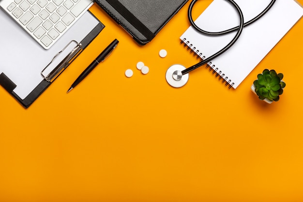 Widok z góry na biurko lekarza z klawiatury stetoskop notatnik i długopis, receptę i pigułki