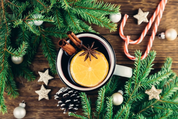 Zdjęcie widok z góry na boże narodzenie i nowy rok pić gorące wino, grzane wino, poncz lub herbatę na drewnianym stole obok zielonego drzewa i świątecznych lasek cukierków.