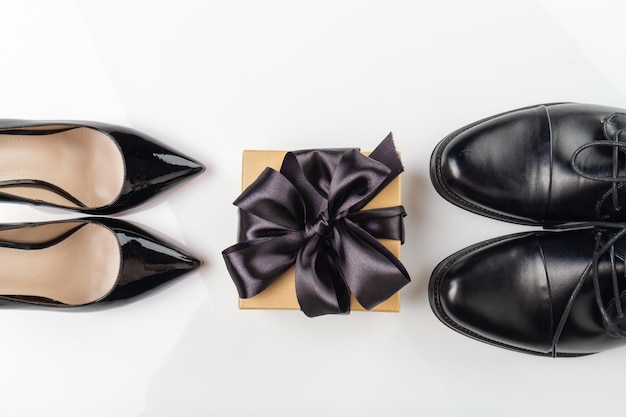 Widok z góry na buty męskie i damskie oraz pudełko z modnymi i stylowymi akcesoriami z czarnej wstążki