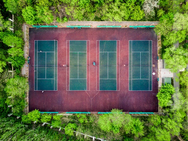 Widok z góry na dół z kortów tenisowych w lesie między drzewami
