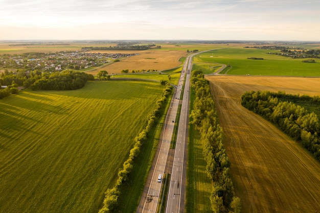 Widok z góry na drogę z samochodami i polami wokół drogi. Pola i drzewa w pobliżu autostrady z poruszającymi się samochodami. Białoruś