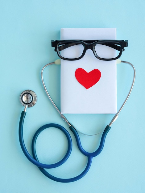 Widok z góry na dzień lekarza Notatnik to okulary czerwone serce stetoskop