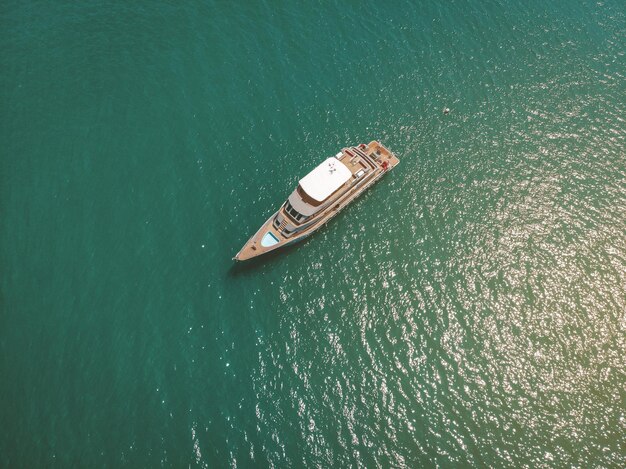 Widok z góry na fajny jacht płynący po Morzu Andamańskim, drewniany pokład, sonda, wyposażenie i turkusowa woda dookoła; koncepcja bogactwa.