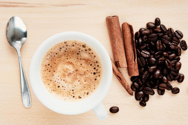 Widok z góry na filiżankę kawy i palonych ziaren kawy na jasnym drewnianym tle
