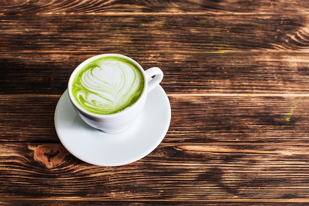 Widok z góry na filiżankę Matcha latte na drewnianym tle. Pojęcie zielonej herbaty jako sztuki