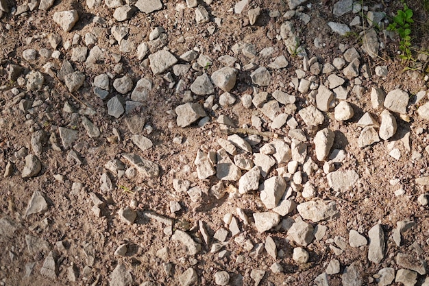 Widok z góry na fragment drogi gruntowej. Suchy ląd z kamieniami. Streszczenie naturalne teksturowanej tło. Kamienie i kamyki na ziemi.