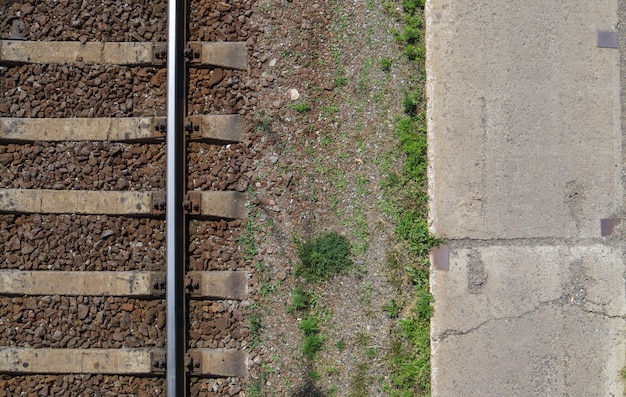 Widok z góry na kolej, leżał płasko. Część toru dla pociągów. Widok z lotu ptaka kolei z drona. Tło z miejscem na tekst. Błyszczące żelazne szyny i podkłady betonowe.