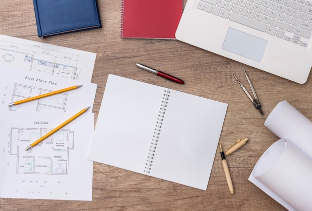 Widok z góry na miejsce pracy architekta z projektem, laptopem i rolkami
