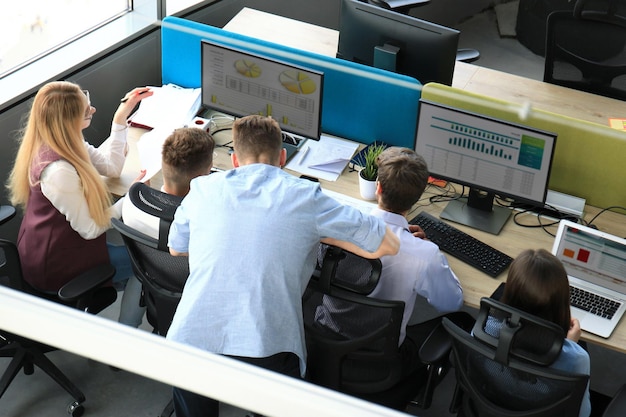 Widok z góry na młodych, nowoczesnych kolegów w eleganckich ciuchach, pracujących razem podczas spędzania czasu w biurze