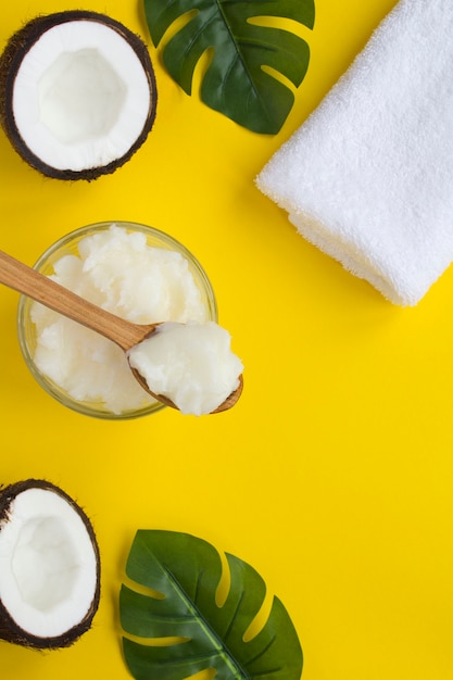 Widok z góry na olej kokosowy, biały ręcznik i połówki orzecha kokosowego