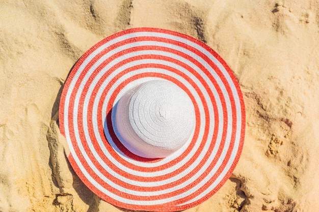 Widok z góry na piaszczystą plażę z czerwonym pasiastym kapeluszem plażowym Tło z miejscem na kopię i widoczną teksturą piasku