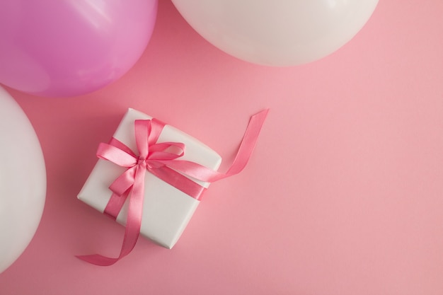 Widok z góry na prezent z różowymi i białymi balonami na różowo