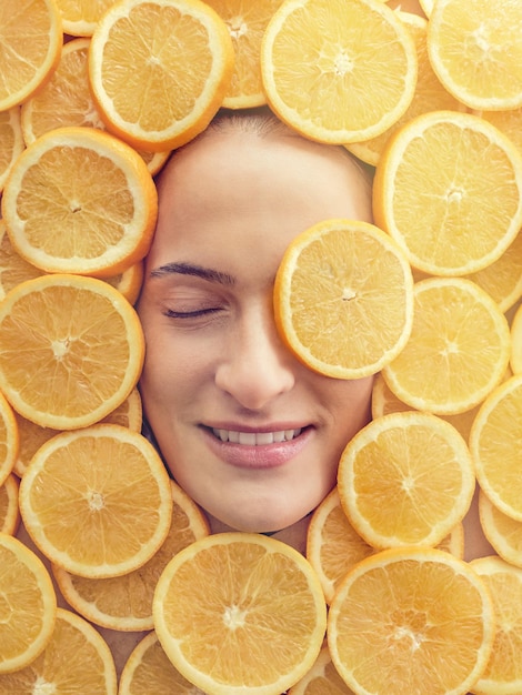 Zdjęcie widok z góry na stos świeżych plasterków pomarańczy z twarzą odpoczywającej kobiety pośrodku