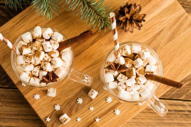 Widok z góry na tradycyjny czekoladowy napój świąteczny z marshmallows w szkle przycięty na drewnianym tle.