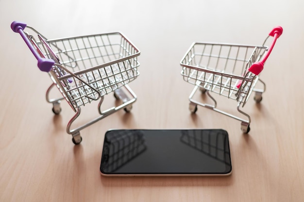 Widok z góry na wózek na zakupy i telefon komórkowy na drewnianym stole Smartphone zakupy online Zakupy online