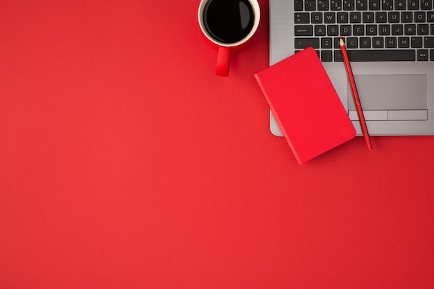 Widok z góry na zdjęcie czerwonego zamkniętego ołówka przypominającego na laptopie i filiżankę kawy na białym tle z copyspace