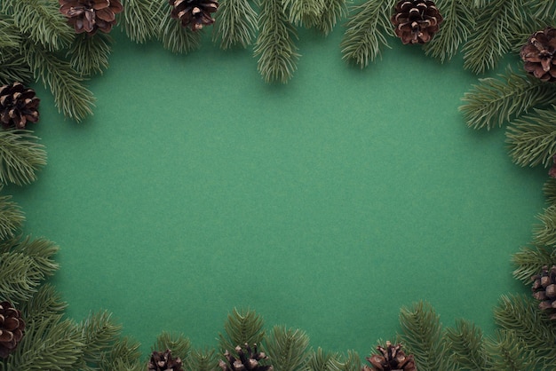 Widok z góry na zdjęcie gałązek sosny z szyszkami na izolowanym zielonym tle z pustą przestrzenią pośrodku