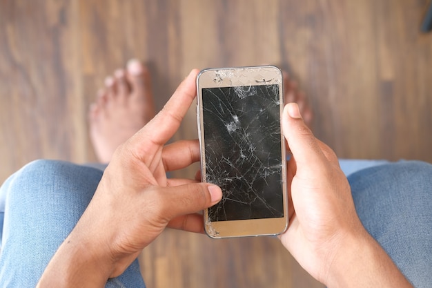 Widok z góry ręki człowieka trzymającego uszkodzony inteligentny telefon