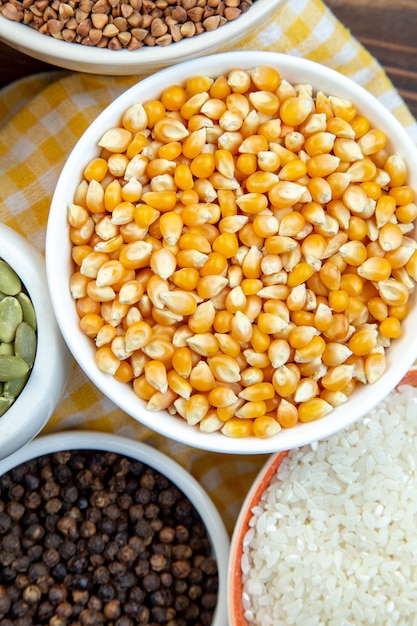 widok z góry różne surowce ryżowe kukurydza soczewica i kasza gryczana w talerzach na brązowej powierzchni