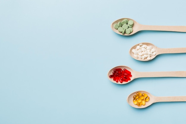 Widok z góry Różnorodność tabletek witaminowych i mineralnych w drewnianej łyżce na kolorowym tle Widok z góry na różne tabletki leków farmaceutycznych Suplement diety Produkt zdrowotny