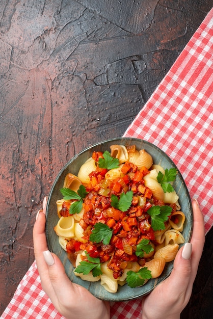 widok z góry smaczny makaron z sosem pomidorowym w misce w kobiecych rękach na drewnianym stole