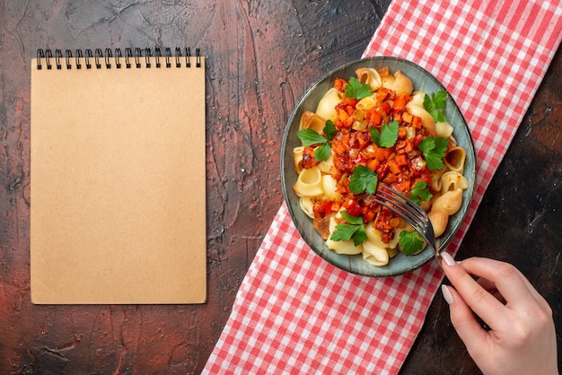 widok z góry smaczny makaron z sosem pomidorowym w misce widelec w żeńskim notatniku na drewnianym stole