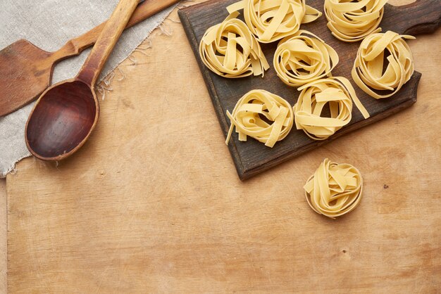 Widok z góry surowego makaronu fettuccine i drewnianą łyżką