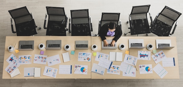 Zdjęcie widok z góry tabeli azjatycki biznes kobieta siedzi i pracuje na laptopie w z wykresów i dokumentów na drewnianym stole konferencyjnym w biurze. koncepcja spotkania biznesowego.