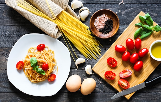 Widok z góry włoskich składników na pomidorowe i bazyliowe spaghetti.