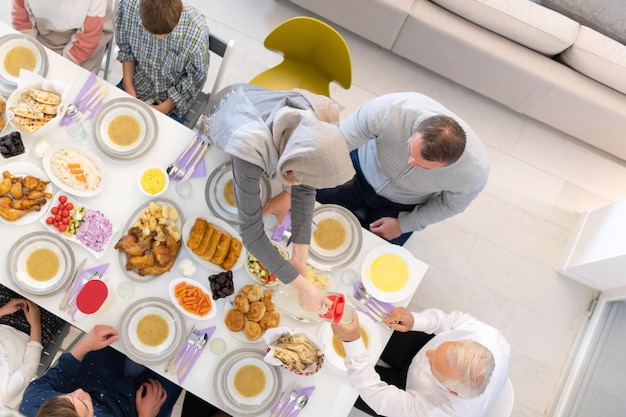 widok z góry współczesnej wieloetnicznej rodziny muzułmańskiej, która lubi jeść razem kolację iftar podczas uczty ramadanu w domu