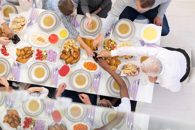 widok z góry współczesnej wieloetnicznej rodziny muzułmańskiej, która lubi jeść razem kolację iftar podczas uczty ramadanu w domu