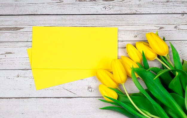 Zdjęcie widok z góry zdjęcia żółte tulipany i koperta na drewnianym tle kopii spce