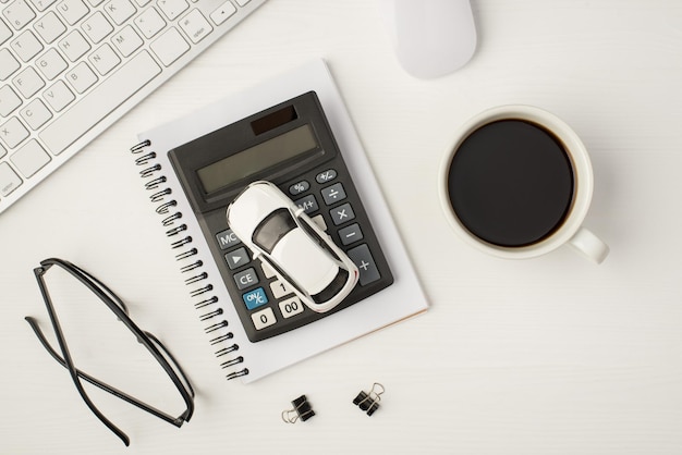 Widok z góry zdjęcie biznesowego miejsca pracy z klawiaturą mysz filiżanka kawy spoiwa okulary model samochodu i kalkulator na notebooku na białym tle