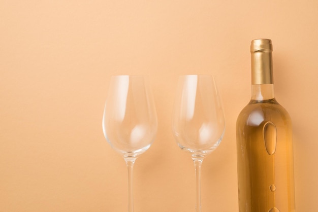 Widok z góry zdjęcie dekoracji świętego walentego, butelka białego wina i dwa kieliszki na odizolowanym pastelowym beżowym tle z copyspace