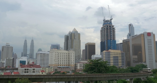 Widok z jazdy pociągiem na kolejach na pierwszym planie i nowoczesnego miasta wieżowiec na tle. Kuala Lumpur, Malezja