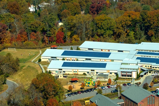 Widok z lotu ptaka budynku szkoły amerykańskiej z dachem pokrytym fotowoltaicznymi panelami słonecznymi do produkcji energii elektrycznej