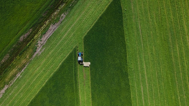 Widok z lotu ptaka ciągnika rolniczego koszącego zielone pole
