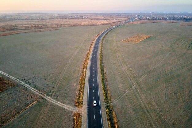 Widok z lotu ptaka drogi międzymiastowej z niewyraźne szybka jazda samochodem o zachodzie słońca. Widok z góry z drona ruchu na autostradzie wieczorem