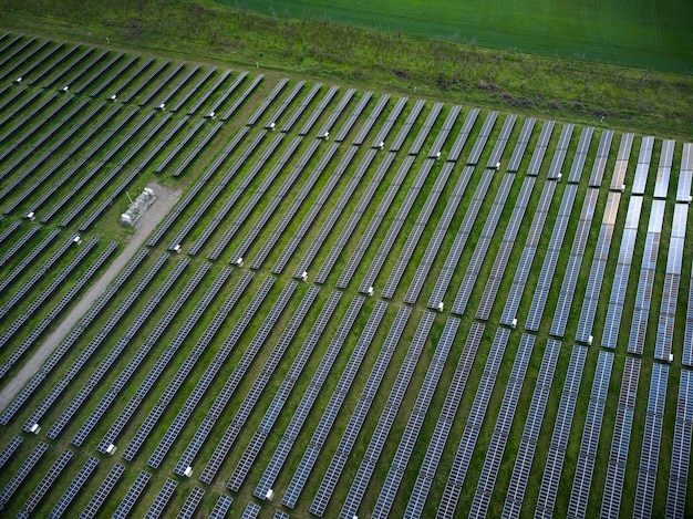 Widok z lotu ptaka drona elektrowni słonecznej w zielonej łące w słoneczny dzień.