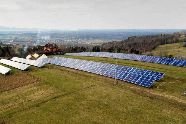 Widok z lotu ptaka dużego pola słonecznego fotowoltaicznego systemu produkującego czystą energię odnawialną na tle zielonej trawy.