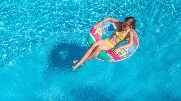 Widok z lotu ptaka dziewczyny w basenie z góry, dziecko pływać na nadmuchiwany pierścień pączka i zabawy w wodzie na rodzinne wakacje