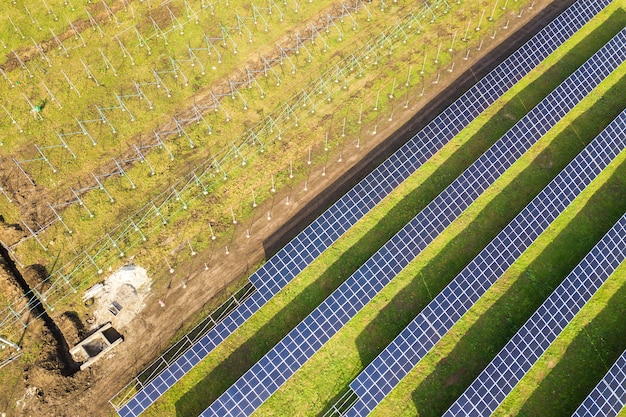 Widok z lotu ptaka elektrowni słonecznej w budowie na zielonym polu. Montaż paneli elektrycznych do produkcji czystej energii ekologicznej.