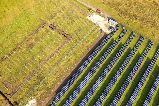 Widok z lotu ptaka elektrowni słonecznej w budowie na zielonym polu. Montaż paneli elektrycznych do produkcji czystej energii ekologicznej.